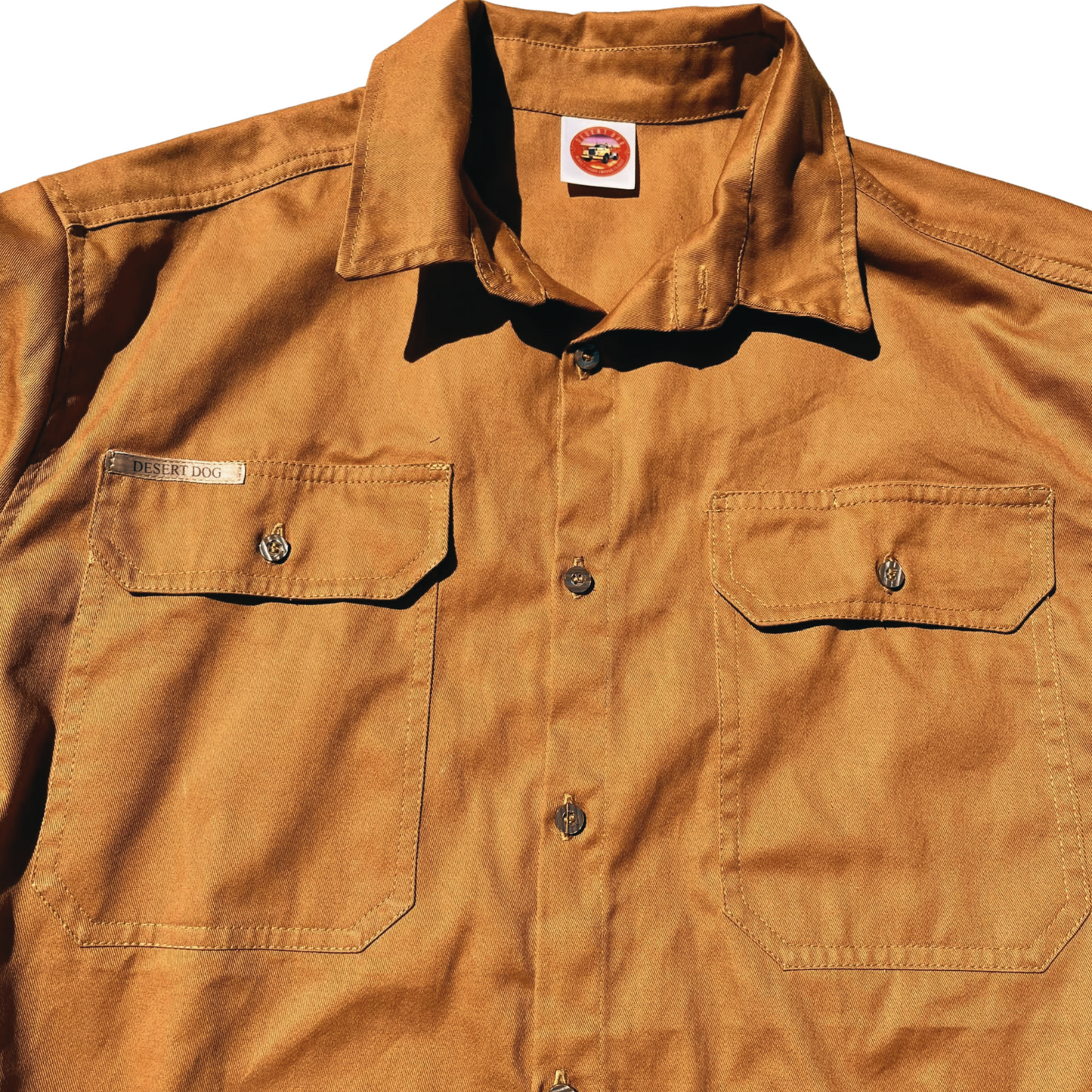A rust coloured flat lay Desert Dog WorkTough shirt showing the pocket, front button and collar detail.