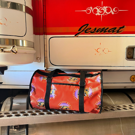 A 25 litre gear bag featuring the Desert Dog signature logo. The bag is sitting on the step of a Western Star prime mover and features the "Jesmat" brand