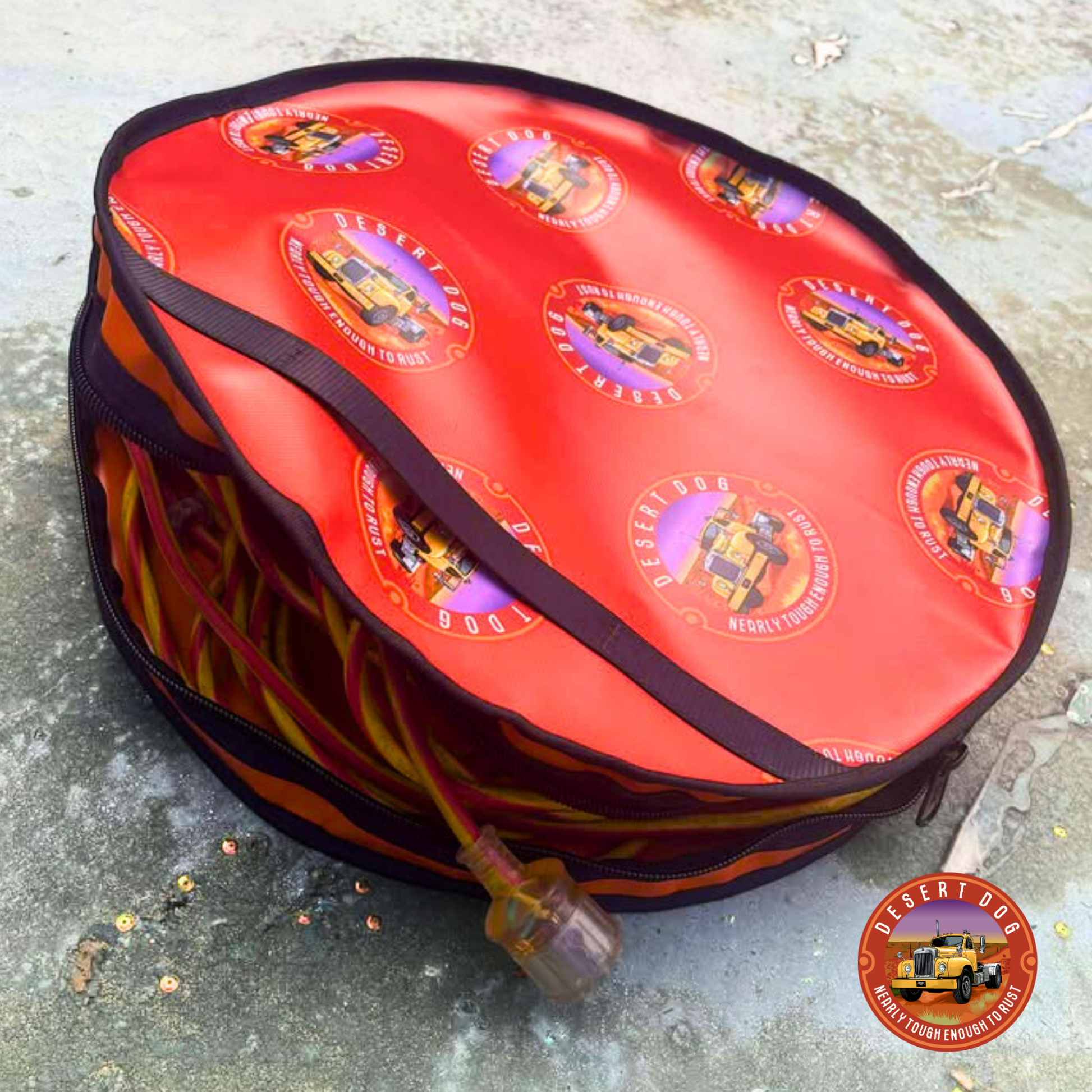 Rust coloured  rope bag with Desert Dog logos. The bag is unzipped and the plug of an extension lead is hanging out of the opening?