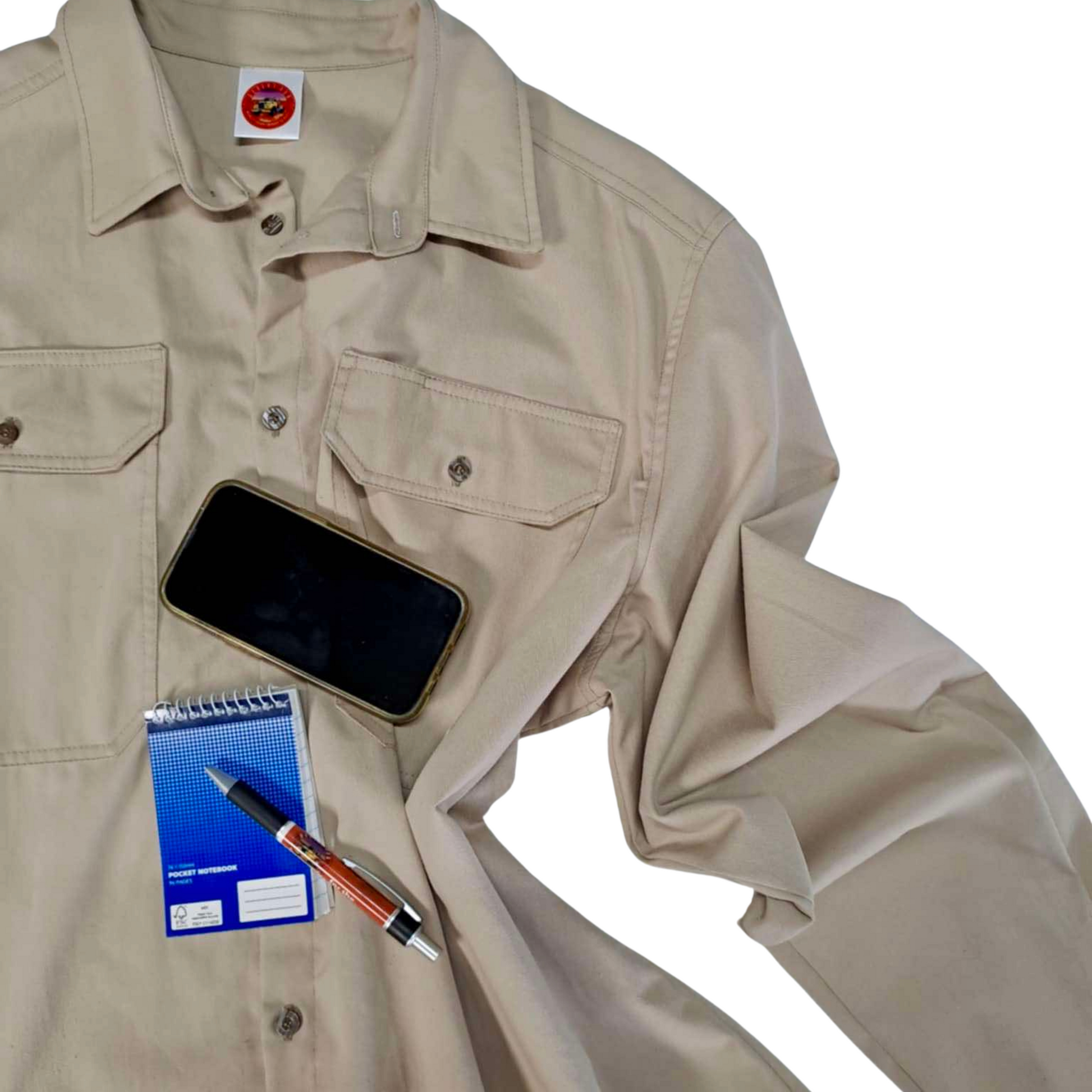 A flat lay Desert Dog WorkTough long sleeved shirt in light beige colour, accessorised with an iphone, small spiral notepad and biro.