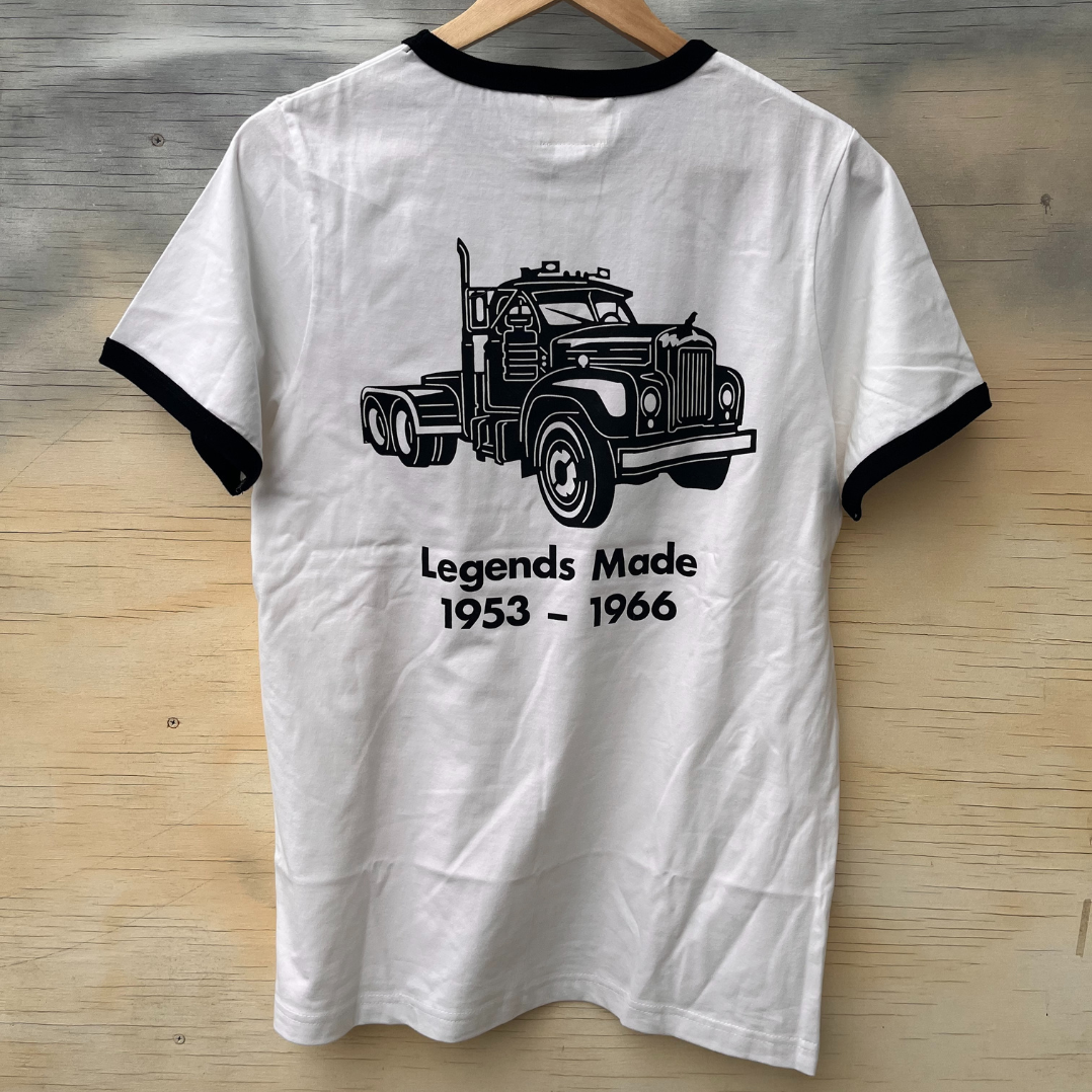 The back of a white ringer style tshirt featuring black binding and the B Model Mack truck and words "Legends Made 1953 - 1966