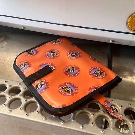A Desert Dog allover logo log book cover placed on the step of a Western Star truck