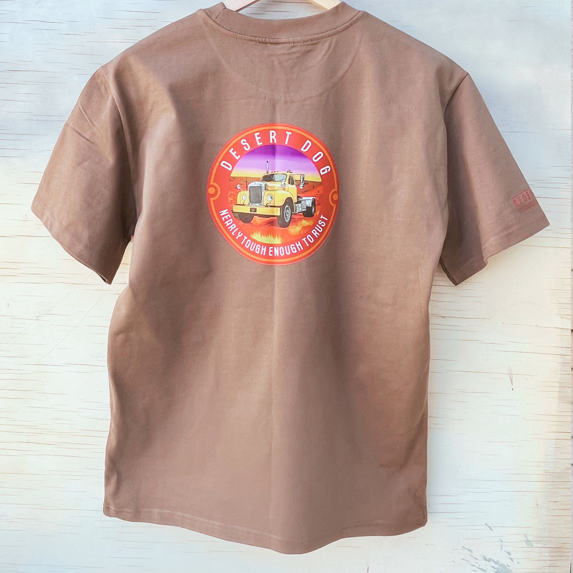 The back of a men's walnut coloured t-shirt, showing the Desert Dog logo featuring a B model Mack truck and the words "nearly tough enough to rust". 