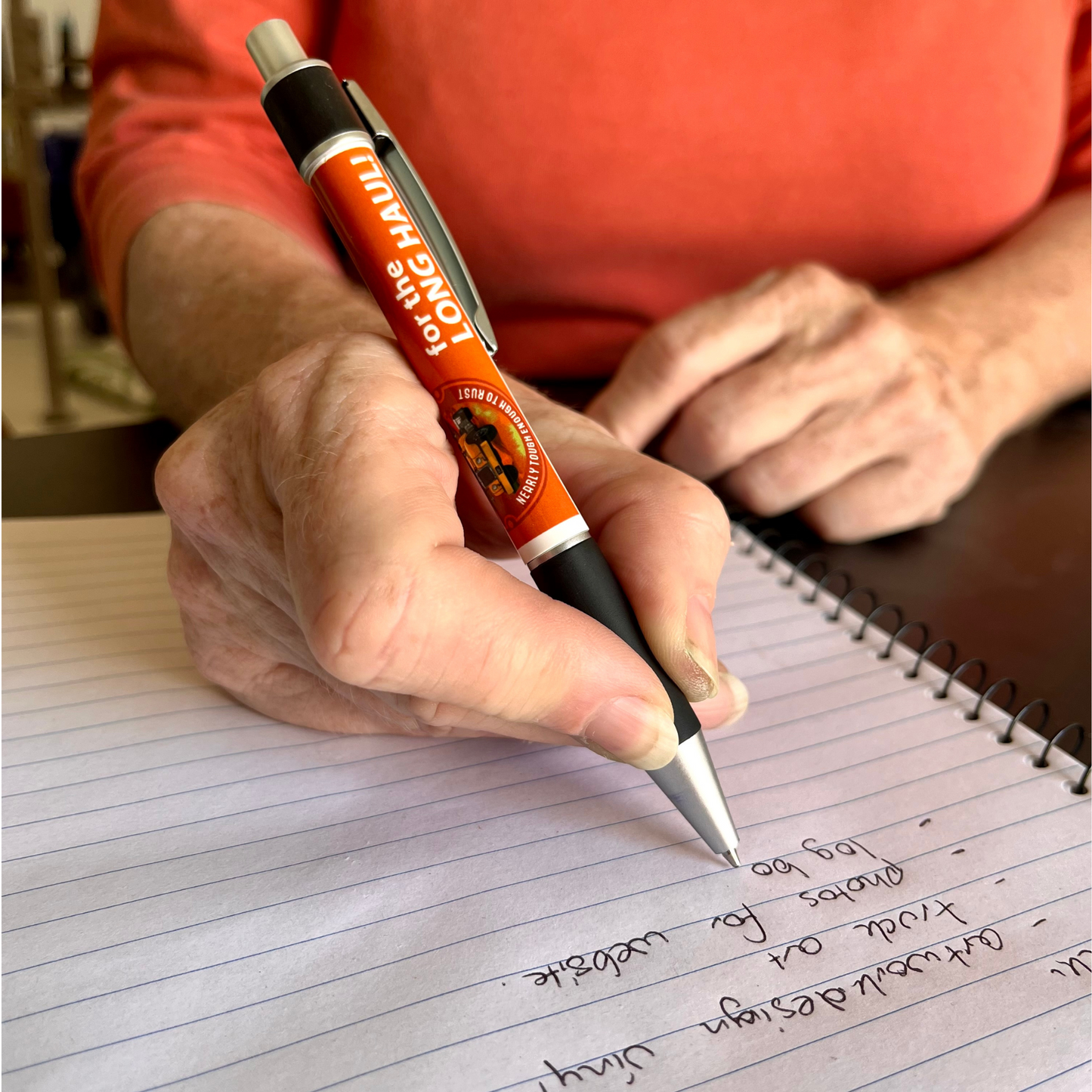 A woman righting a list using the desert dog branded pen which comes free with every log book cover.