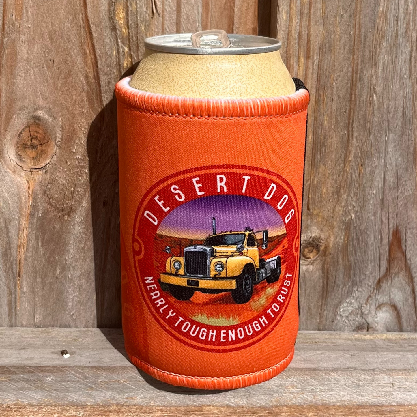 Signature orange stubby holder with the Desert Dog logo of a B model Mack truck sitting on a wooden fence