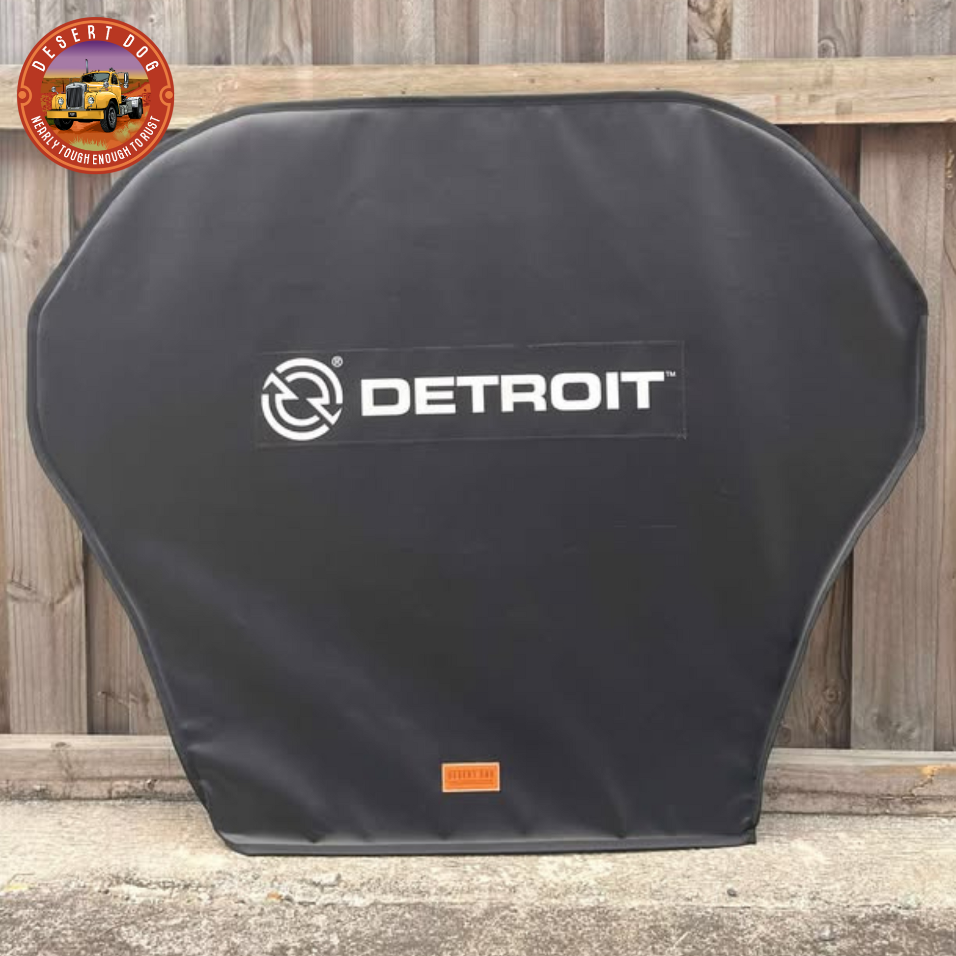 Black turn table cover with 'Detroit' logo leaning against a wooden fence