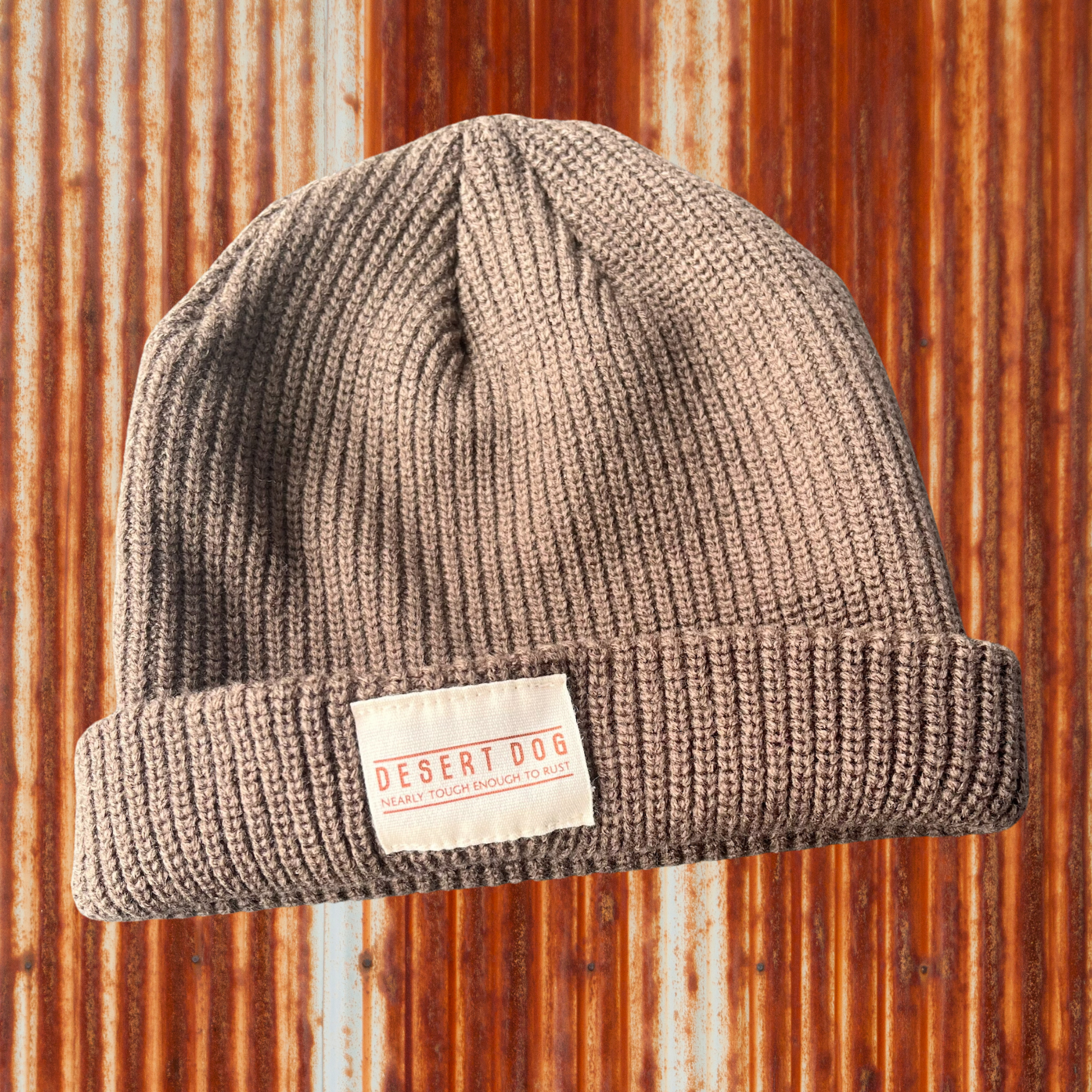 Light brown coloured beanie labelled Desert Dog, nearly touch enough to rust, with a rusty tin wall background 