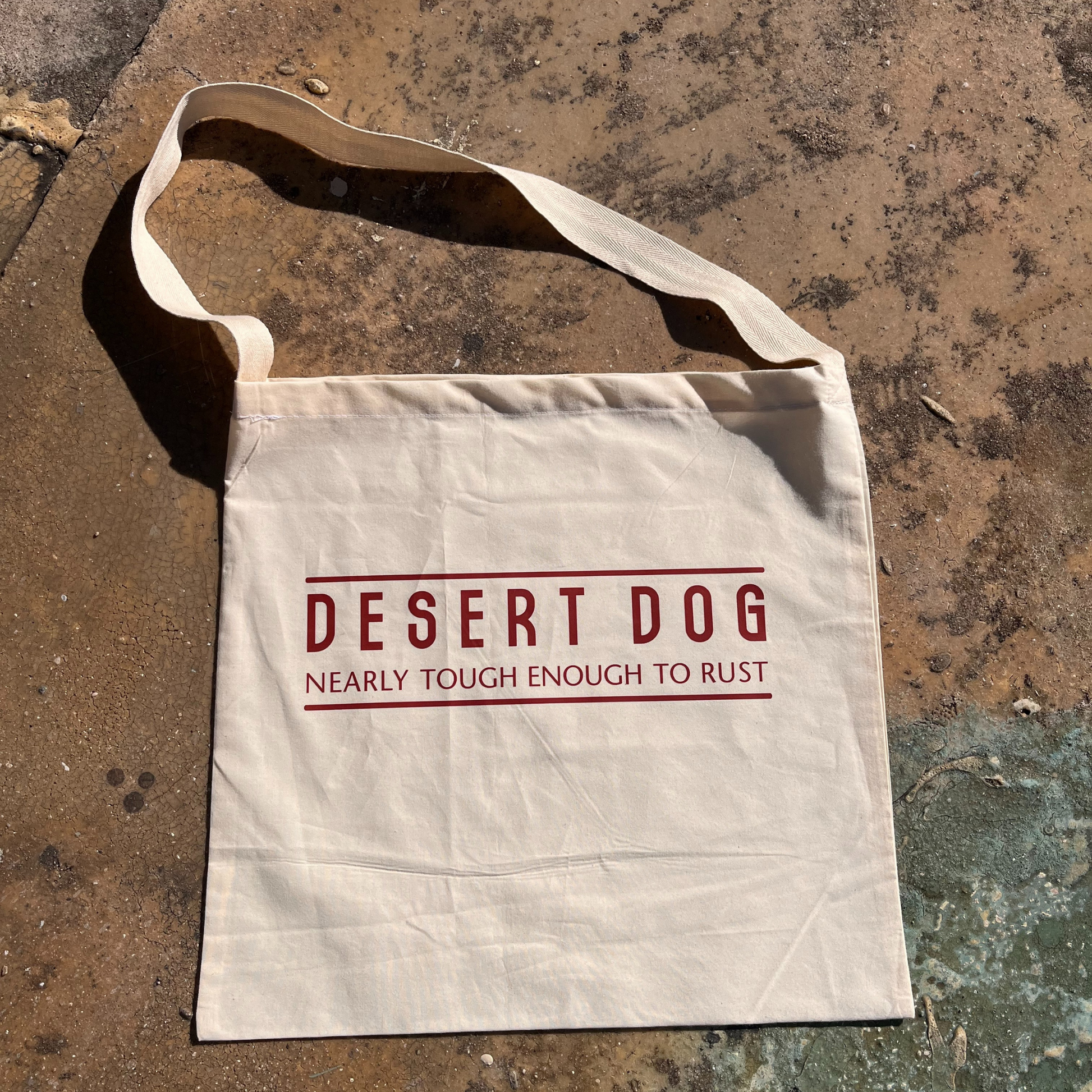 A calico tote bag with a Desert Dog text logo